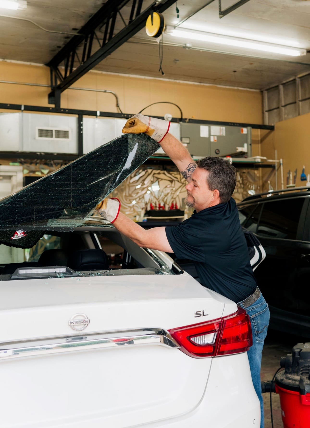 Technician applying window tint to a side window in the shop